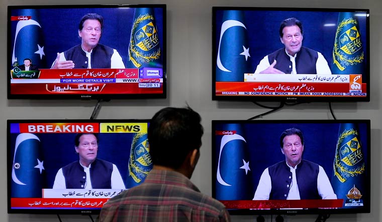A man watches news channels broadcast a live address to the nation by Pakistan's Prime Minister Imran Khan, in Islamabad | AP
