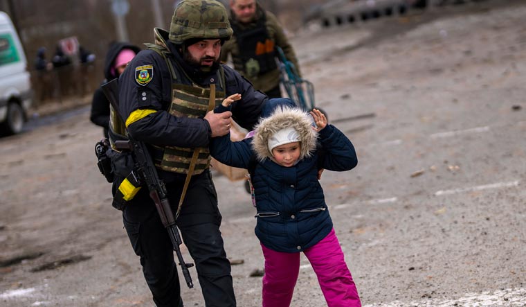 A Ukrainian police officer helping a child fleeing Irpin | AP