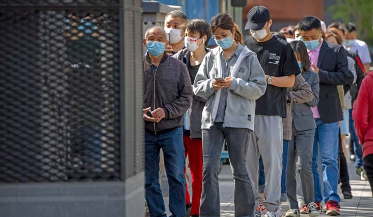People wearing face masks stand in line for coronavirus tests in a neighborhood in the Dongcheng district of Beijing, Tuesday, April 26, 2022 | AP