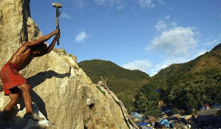 File: A miner breaks stones containing gold in Poboya in Indonesia's Central Sulawesi province April 12, 2012 | Reuters