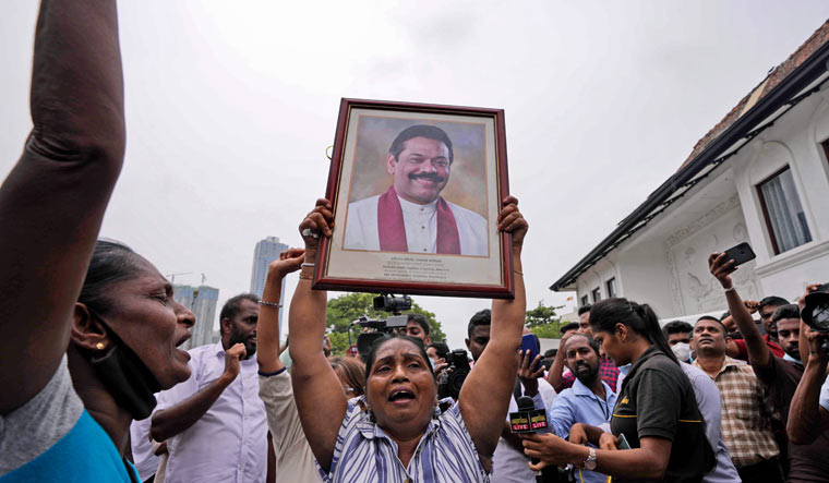 Sri Lankan government supporters shout slogans holding a portrait of prime minister Mahinda Rajapaksa outside his official residence in Colombo, Sri Lanka, Monday, May 9, 2022 | AP