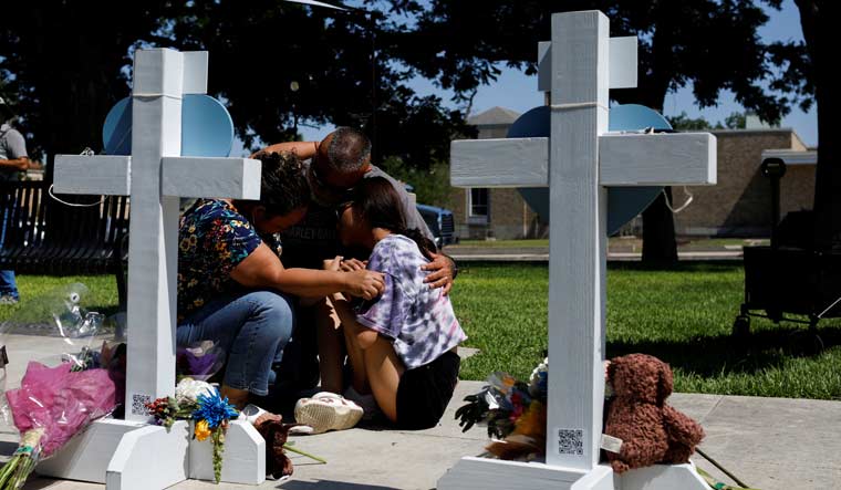 People mourn at a memorial in Town Square in front of the county courthouse, two days after a gunman killed 19 schoolchildren and two teachers, in Uvalde, Texas | Reuters