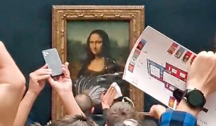 A security guard cleans smeared cream from the glass protecting the Mona Lisa at the Louvre Museum, in Paris, France, Sunday, May 29, 2022 | AP