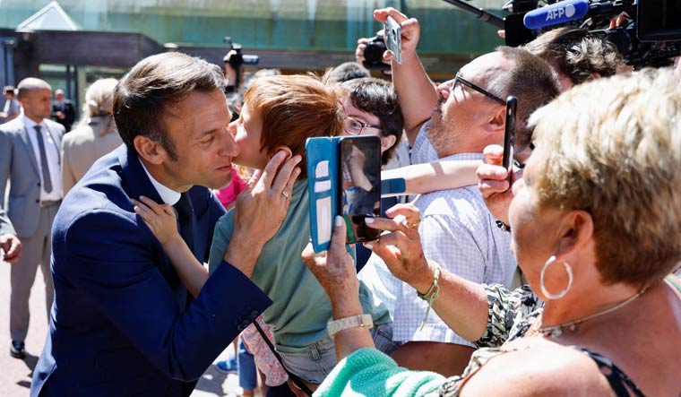 French President Emmanuel Macron kisses a child during the first round of French parliamentary elections, at a polling station in Le Touquet, France, June 12, 2022 | Reuters