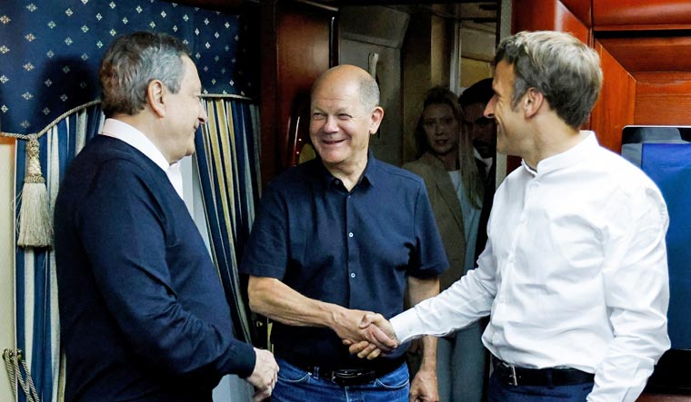 French President Emmanuel Macron shakes hands with German Chancellor Olaf Scholz next to Italian Prime Minister Mario Draghi as they travel on board a train bound to Kyiv after departing from Poland, June 16, 2022 | Reuters