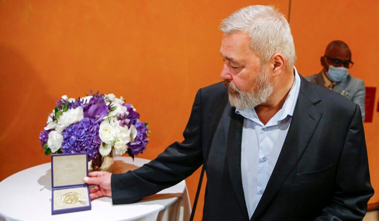 Nobel Peace Prize winner Dmitry Muratov, editor-in-chief of the influential Russian newspaper Novaya Gazeta, looks at his 23-karat gold medal as he poses for a picture next to it before the medal is auctioned at the Times Center, Monday, June 20, 2022, in New York. (AP Photo/Eduardo Munoz Alvarez)