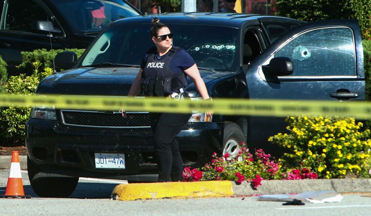A police officer walks next to a car with bullet holes on the windows at a crime scene after authorities alerted residents of multiple shootings targeting transient victims in the Vancouver suburb of Langley, British Columbia, Canada July 25, 2022.  REUTERS/Jesse Winter