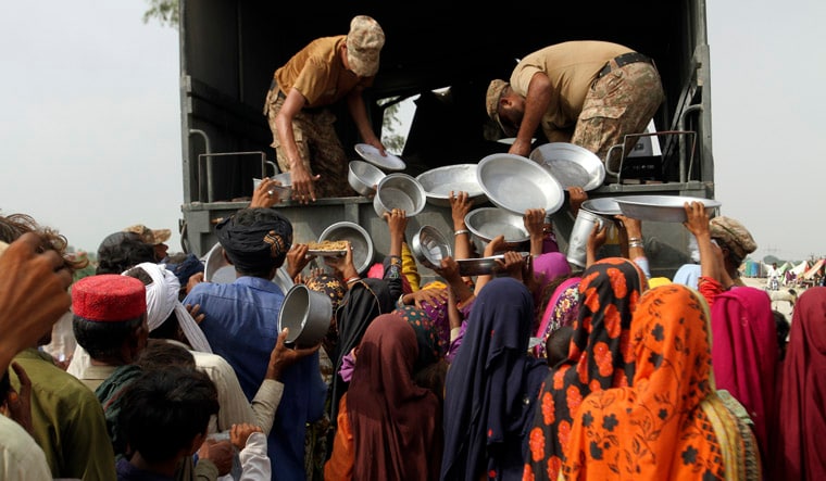 Army troops distribute food and other stuff to displace people in a flood-hit area in Rajanpur, district of Punjab, Pakistan, Saturday, Aug. 27, 2022. Officials say flash floods triggered by heavy monsoon rains across much of Pakistan have killed nearly 1,000 people and displaced thousands more since mid-June. (AP Photo/Asim Tanveer)