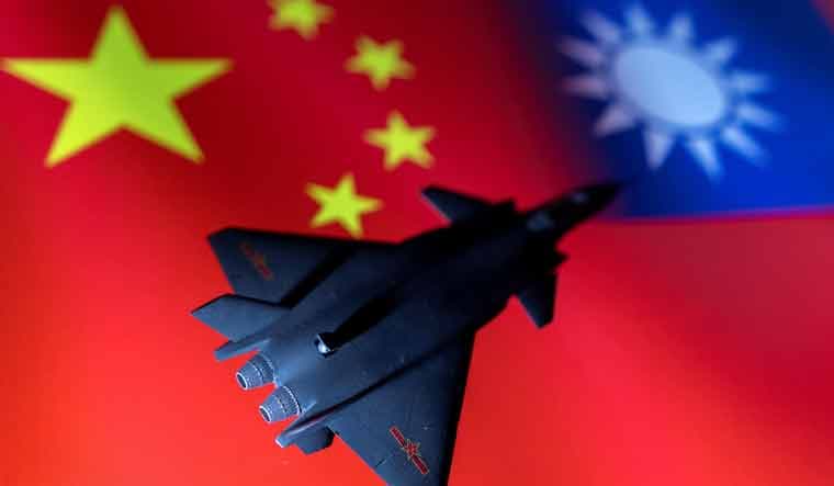 A model of the Chinese Fighter aircraft is seen in front of Chinese and Taiwanese flags | Reuters