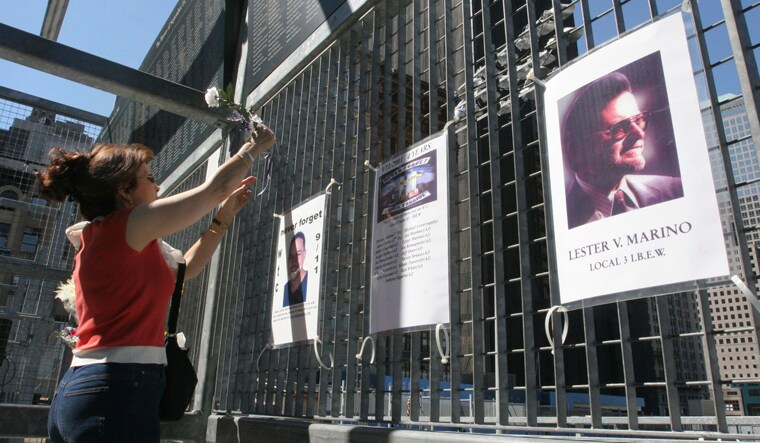FILE - Kathy Haberman places a flower and card in memory of her daughter Andrea Haberman on a gate with other memorial images surrounding ground zero, the site where the World Trade Center once stood in New York, Saturday, Sept. 10, 2005. Andrea Haberman lost her life in the September 11, 2001 World Trade Center attacks. As Sunday's 21st anniversary of the terror attacks approaches, Mohammed and four other men accused of 9/11-related crimes still sit in a U.S. detention center in Guantanamo Bay, their planned trials before a military tribunal endlessly postponed. (AP Photo/Tina Fineberg, File)