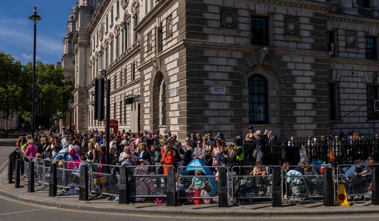 Well-wishers camp along a fence barricade to watch the Queen Elizabeth II funeral ceremonies in London | AP