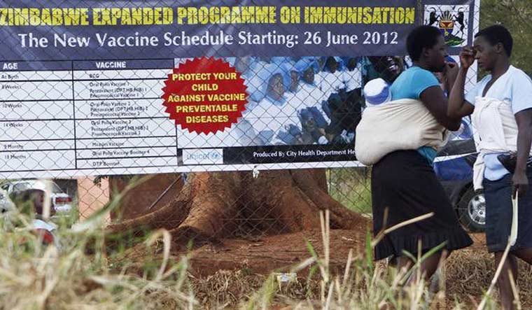 File: Mothers walk past a billboard encouraging immunisation against polio and measles at a clinic in Harare June 21, 2012 | Reuters