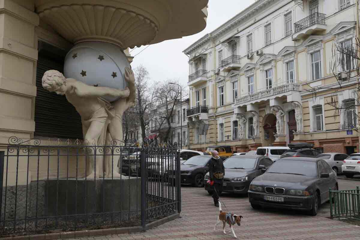 A woman walks with a dog next to a building in the historical city centre, amid Russia’s attack on Ukraine, in Odesa | Reuters
