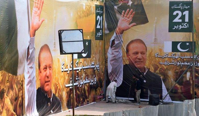 Workers give final touches next to huge portraits of Pakistan's former Prime Minister Nawaz Sharif displayed at the venue of his welcoming rally, in Lahore, Pakistan on October 21, 2023 | AP