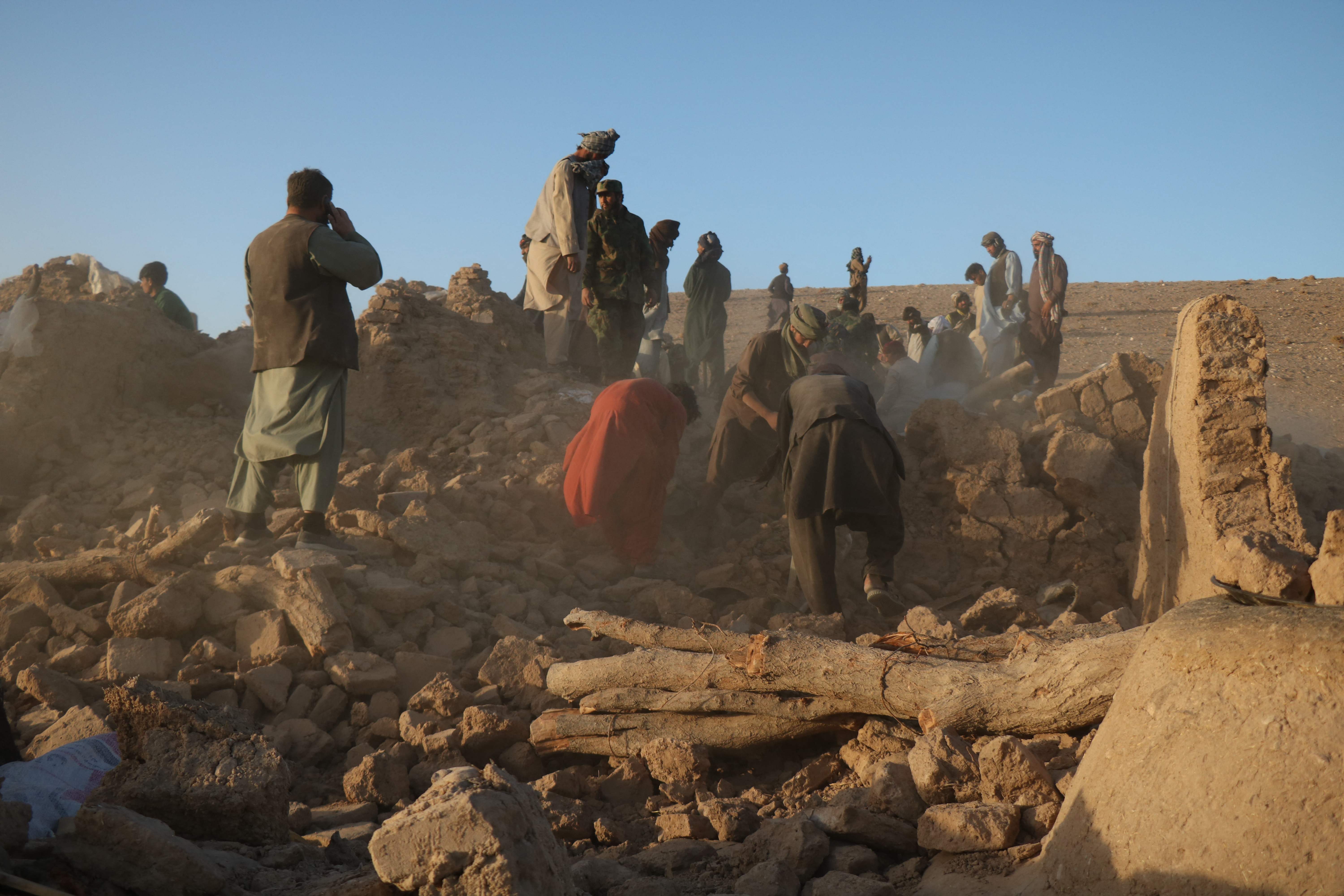 Afghan residents clear debris from a damaged house after earthquake