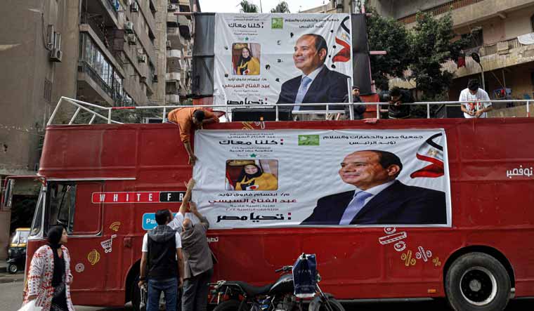 Supporters hang a campaign banner of Egypt's President Abdel Fattah al-Sisi at a bus on a street in Cairo on December 7, 2023, ahead of the country's presidential election | AFP