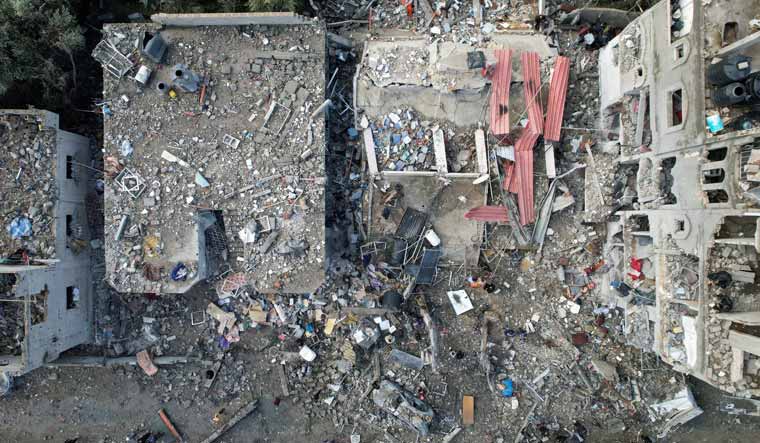 Palestinians gather at the site of Israeli strikes on houses, amid the ongoing conflict between Israel and the Palestinian Islamist group Hamas, at the Maghazi camp in the central Gaza Strip | Reuters