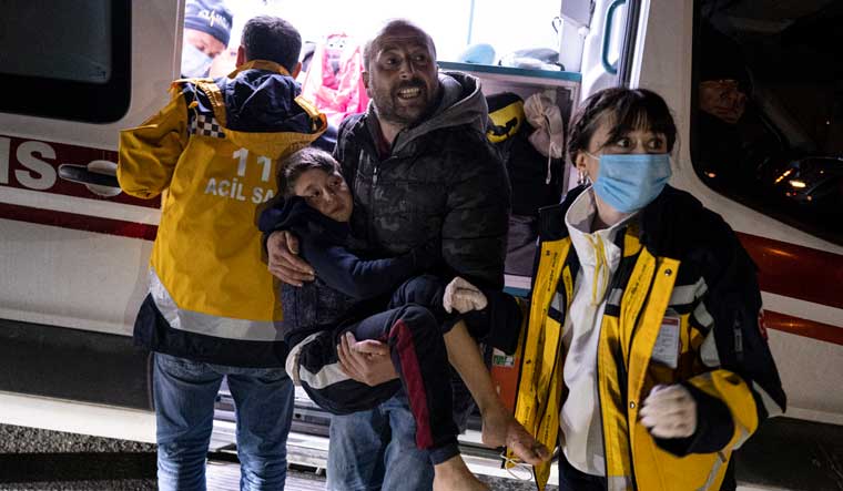 A boy is taken to an ambulance after being injured during the latest earthquake in Hatay, Turkey, on February 20 | AP
