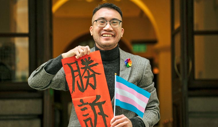 Transgender activist Henry Edward Tse holding a sign written 'Legal Victory' and a flag of transgender identity poses for a photograph outside of Court of Final Appeal in Hong Kong, Monday, Feb. 6, 2023 | AP