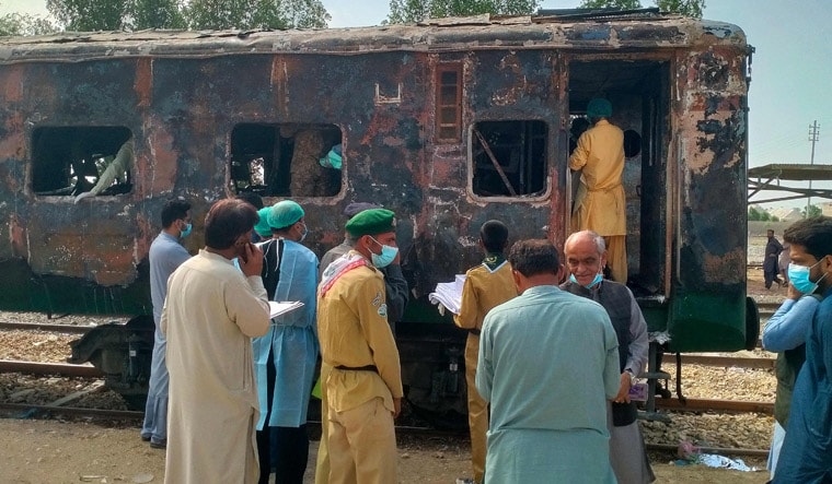 Security officials search for victims inside a burnt out carriage following an overnight fire in the Karachi Express passenger train near Sukkur, some 450 km north of the port city of Karachi on April 27, 2023. - At least seven people, including five of a family, died when a vagon of a passanger train caught fire in southern Pakistan overnight, an offical on April 27 said. (Photo by Shahid ALI / AFP)