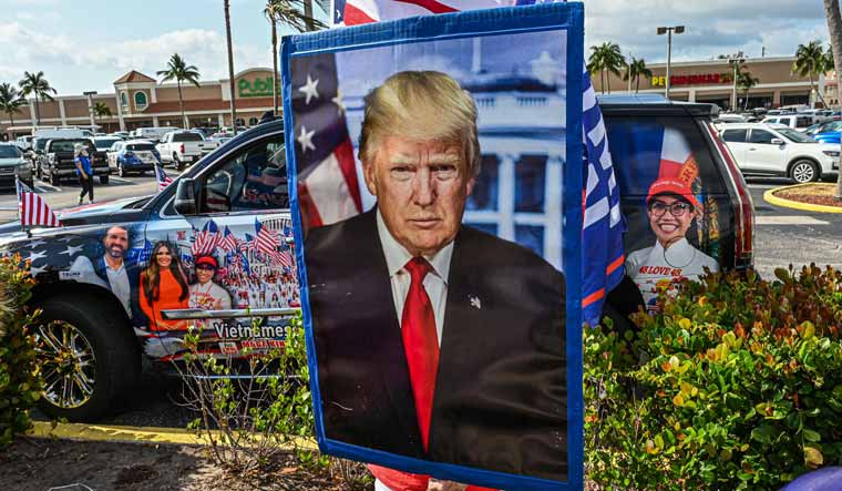 Supporters of former US president Donald Trump react as his motorcade makes its way to Palm Beach International Airport in Palm Beach, Florida | AFP