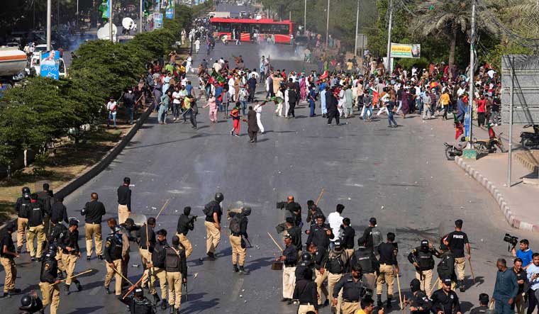 Police officers and supporters of Pakistan's former Prime Minister Imran Khan exchange stones during a protest against the arrest of Khan, in Karachi | AP