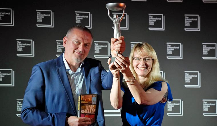 Bulgarian writer Georgi Gospodinov, left, holds up the winner's trophy after his book "Time Shelter" translated from Bulgarian by Angela Rodel, right, won The International Booker Prize 2023, in London, Tuesday, May 23, 2023 | AP