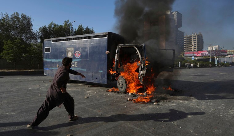 A man runs past a burning prison van set on fire by angry supporters of Pakistan's former Prime Minister Imran Khan during a protest against the arrest of their leader, in Karachi, Pakistan, Tuesday, May 9, 2023. Khan was arrested Tuesday as he appeared in a court in the country‚Äôs capital, Islamabad, to face charges in multiple graft cases. Security agents dragged Khan outside and shoved him into an armored car before whisking him away. AP/PTI(AP05_09_2023_000215B)