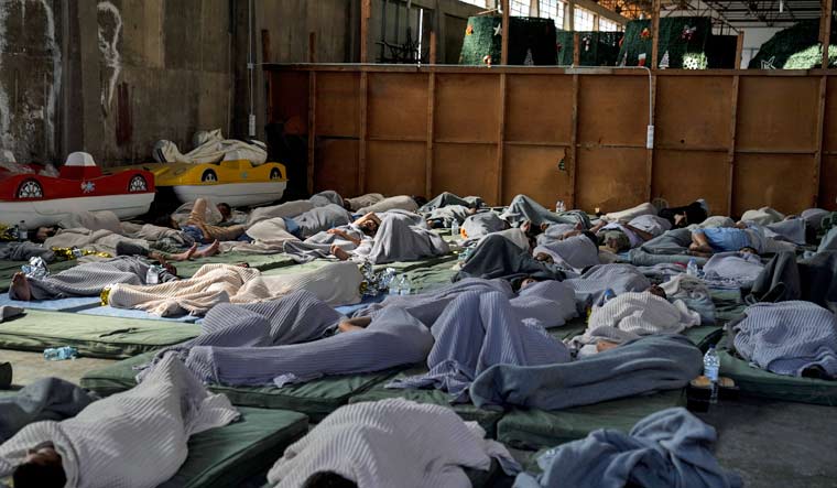 Survivors of a shipwreck sleep at a warehouse at the port in Kalamata town, about 240 kilometers (150 miles) southwest of Athens, June 14, 2023 | AP