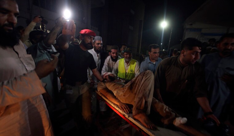 People transport an injured victim of a powerful bomb upon arrival at a hospital in Peshawar, Pakistan, Sunday, July 30, 2023. A bomb ripped through a rally by supporters of a hard-line cleric and political leader in the country's northwestern Bajur district that borders Afghanistan on Sunday, police and health officials said. (AP Photo/Muhammad Sajjad)