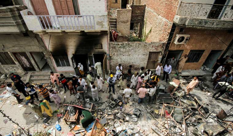 People and members of the media gather along a street in a Christian neighbourhood, a day after the church buildings and houses were vandalised by protesters in Jaranwala, Pakistan August 17, 2023 | Reuters