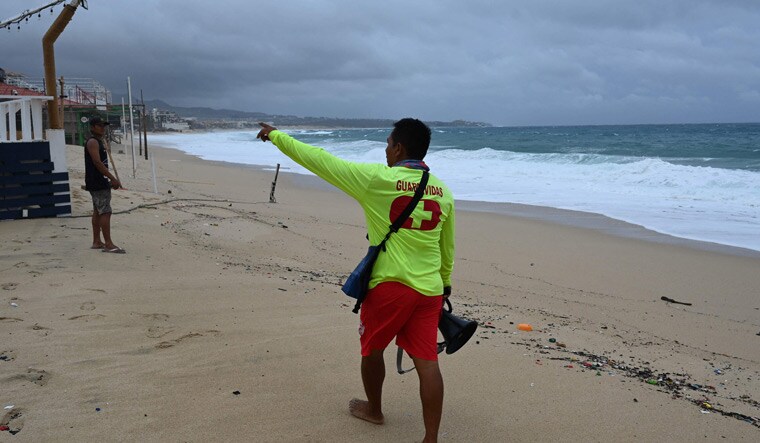 Local government lifeguard Julio Cesar Tehuitzin asks a young man to leave the beach in Los Cabos, Baja California State, Mexico, during the passage of Hurricane Hilary | AFP