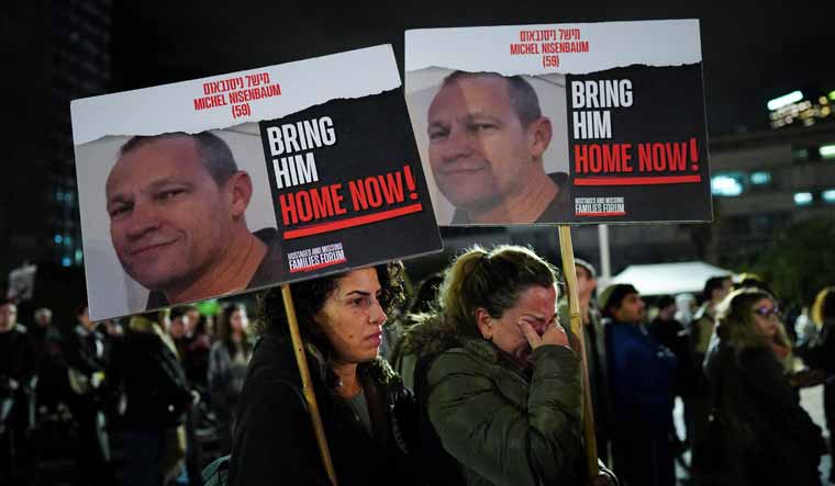 Ayala Harel holds a placard depicting her uncle calling for the release of Israeli hostages in Gaza,  in Tel Aviv | Reuters 