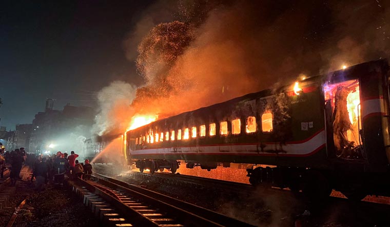 Firefighters try to extinguish a fire caught on a passenger train, ahead of the general election in Dhaka, Bangladesh | Reuters