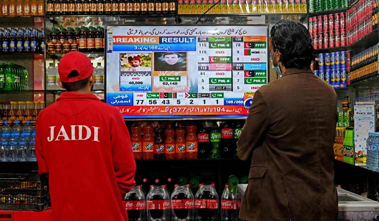People watch latest election results live on a television at a shop, a day after Pakistan's national elections, in Lahore | AFP