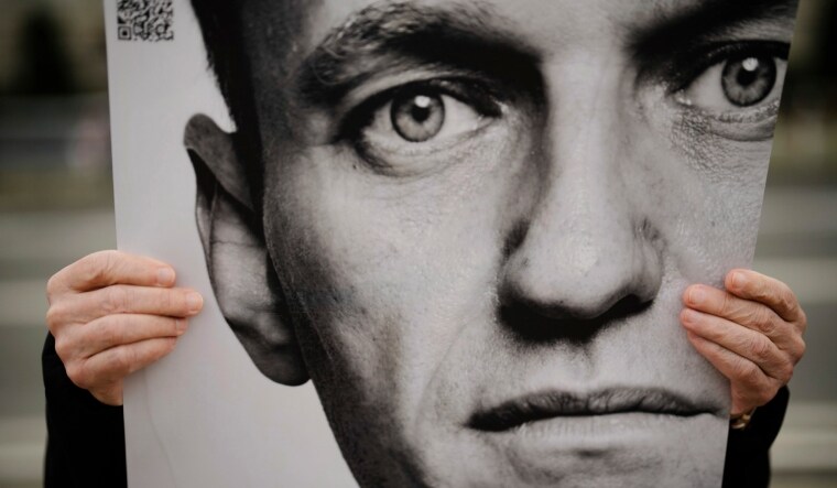 A man holds a poster with a portrait of opposition leader Alexei Navalny during a protest in front of the Russian embassy in Berlin | AP