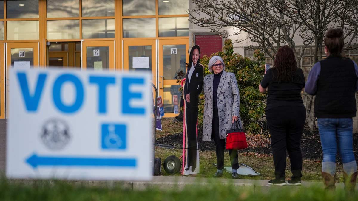 A voter poses for a cardboard cutout of Democratic presidential nominee Vice President Kamala Harris before voting opens at Scranton High School in Scranton, Pa. | AP