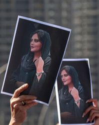 Women hold up pictures of Mahsa Amini | AFP
