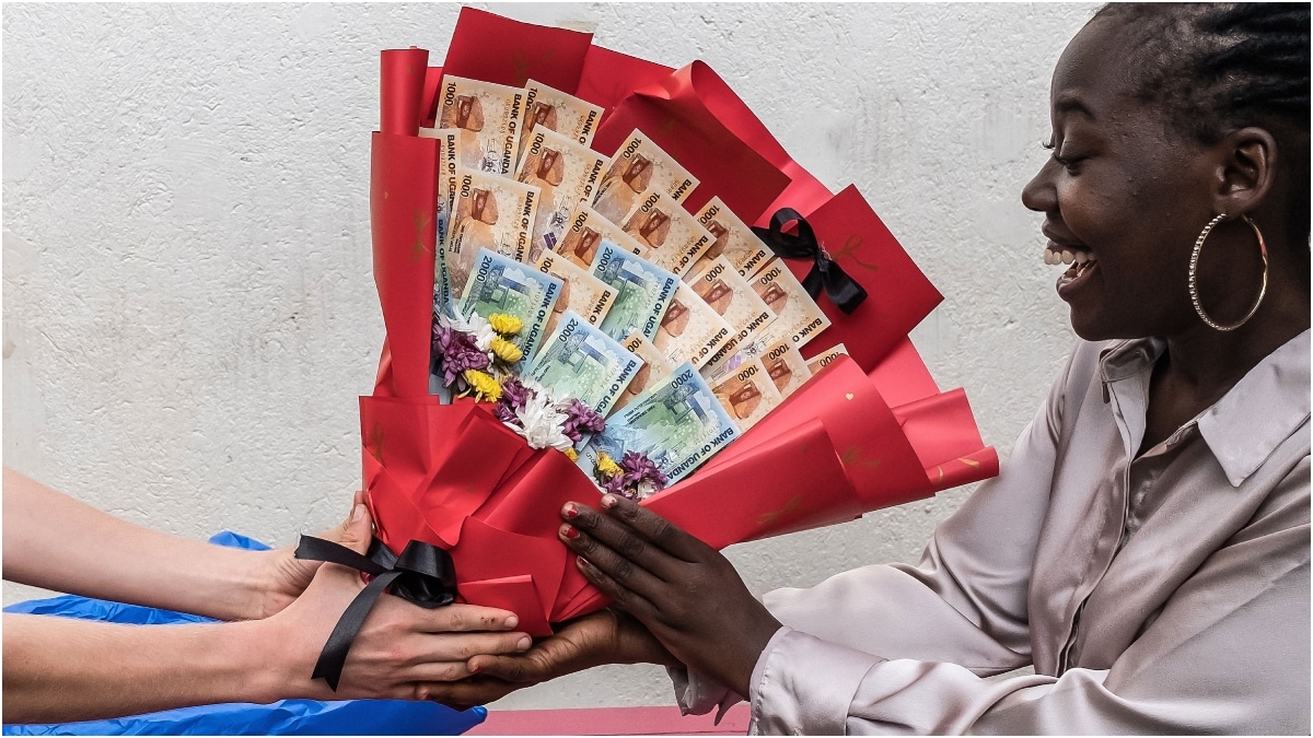 A woman reacts as she receives a bouquet made of banknotes and flowers from her boyfriend as a surprise ahead of Valentine's Day during a hangout in Kenya's Kampala | AFP