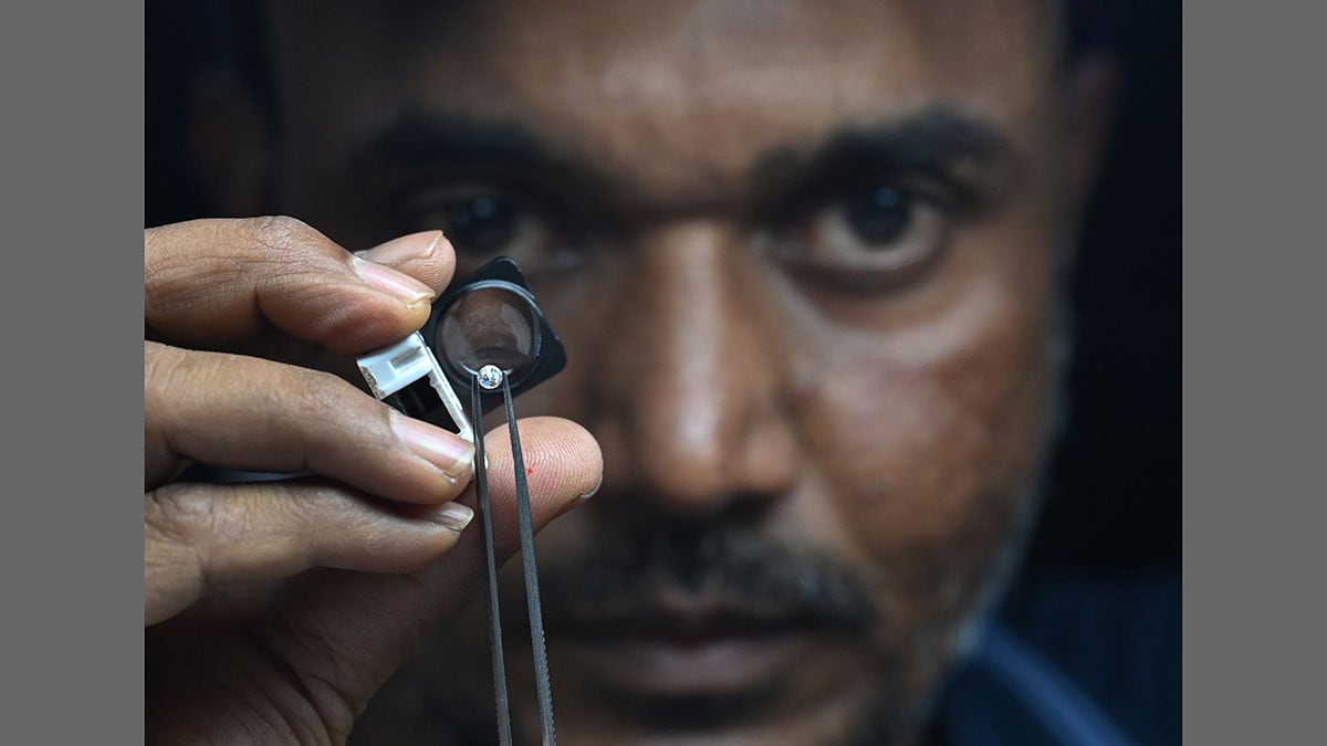 Hard times: A worker inspects a polished diamond at a diamond unit in Surat | Amey Mansabdar
