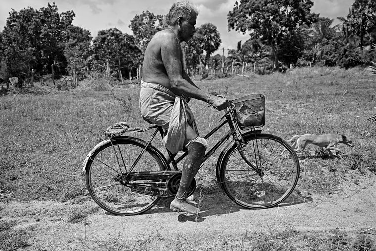 Veerakatti Vetrivelayuthapillai, a landmine victim, pedals to his plantain farm.