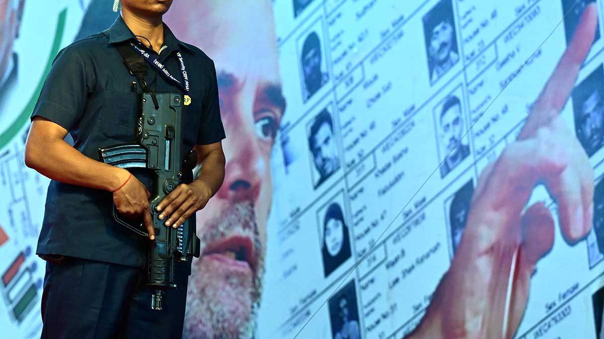 Taking aim: A screen behind a security personnel shows Rahul Gandhi speaking at a public rally in Bengaluru | Bhanu Prakash Chandra