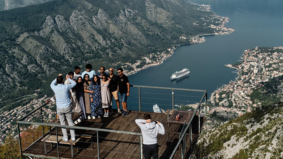 Affordable gateway: A group of tourists poses on an observation deck overlooking the Bay of Kotor | Shutterstock