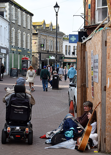 Nowhere to go: An elderly man rides a scooter past a young couple sleeping rough in the Newquay town centre in Cornwall. Increasing poverty is a major concern for the new government | Shutterstock