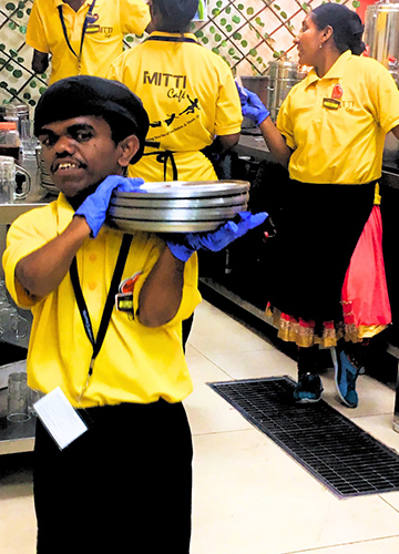 Bhairappa Biradur, who has dwarfism with motor and mild intellectual disabilities, leads the team at the café at the airport.