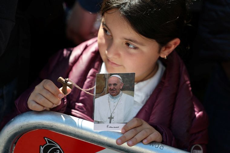 Love and prayers: A girl holds a picture of Pope Francis as she waits for his coffin to arrive at Santa Maria Maggiore | Reuters