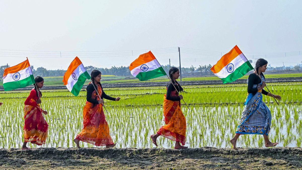 Women carry the tricolour as they walk through a paddy field, on the eve of Independence Day in West Bengal on August 14 2025 | PTI 