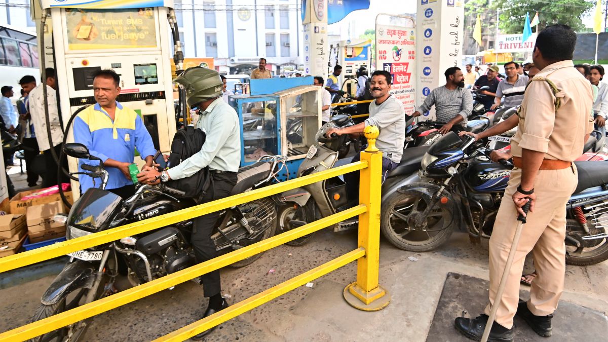 A police personnel keeps vigil as people queue up at a petrol pump amid rumours of fuel shortage in Uttar Pradesh | X 