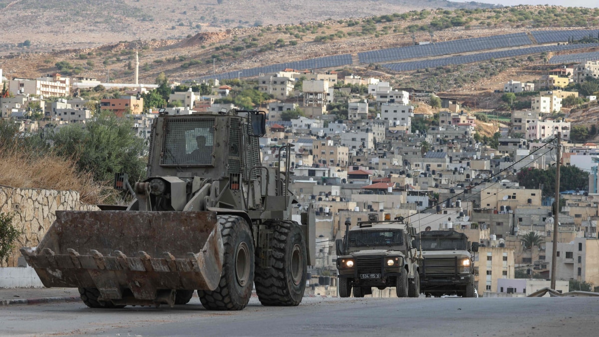 Israeli military vehicles, led by an armoured bulldozer, on the move during a raid | AFP