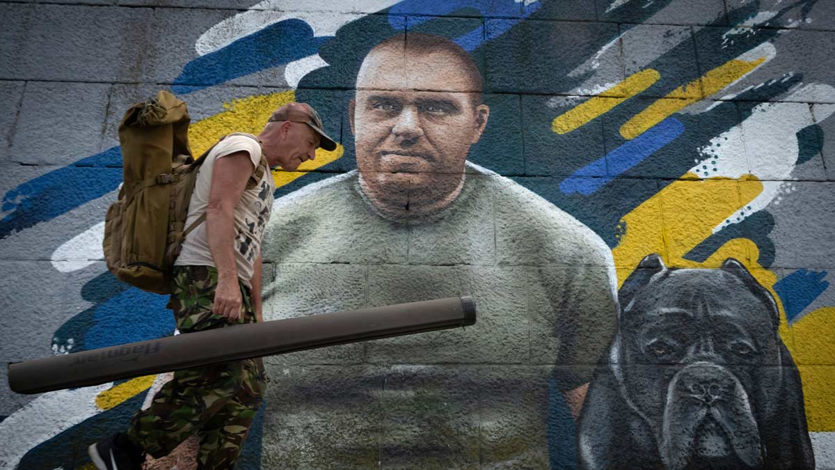 A fisherman passes by a mural in Kyiv, Ukraine depicting the head of Ukraine's Security Service Vasyl Malyuk who led Operation Spiderweb